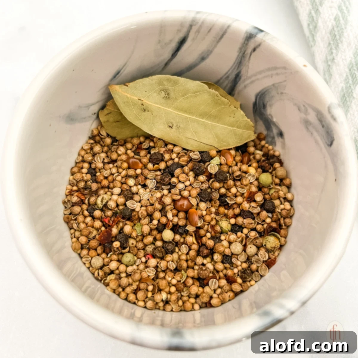 Signature Corned Beef Spice Blend 8 Close-up shot of homemade corned beef seasoning in a ceramic bowl, with a small silver spoon, showcasing its rich texture and vibrant colors.