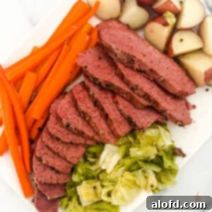 Slow-Braised Dutch Oven Corned Beef 11 Sliced Dutch oven corned beef with vegetables on the side.