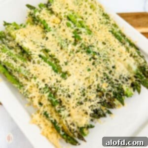 Creamy Asparagus Cheese Bake 11 Asparagus casserole on a white serving plate, garnished with fresh herbs.