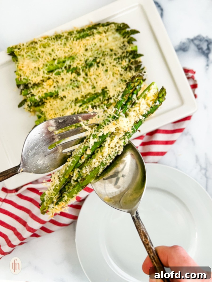 Creamy Asparagus Cheese Bake 3 Getting a portion of baked parmesan asparagus using spoon and fork, highlighting the crispy topping.