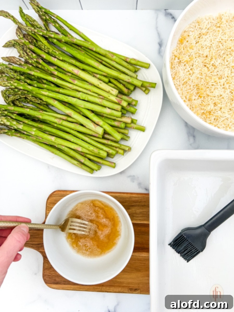 Creamy Asparagus Cheese Bake 8 Prepared ingredients for parmesan cheese and asparagus casserole, including whisked egg white and maple syrup.