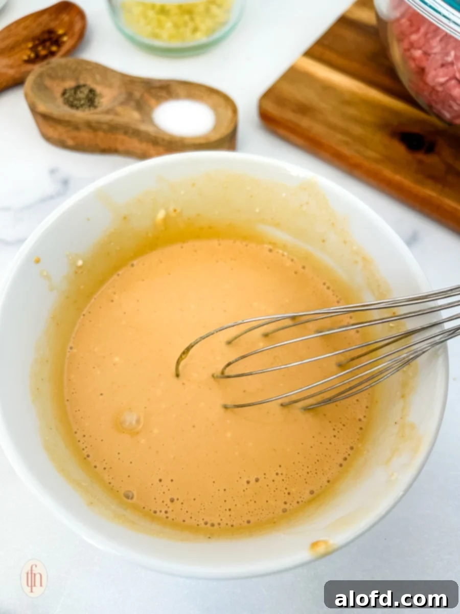 Dynamite Meatballs 5 Sauce on a mixing bowl with whisk for firecracker meatballs.