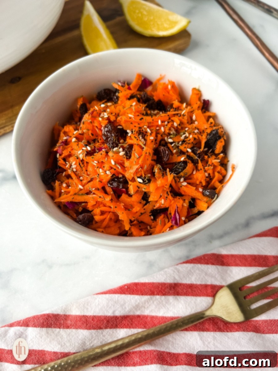 A bowl of freshly prepared shredded carrot salad, garnished with fresh herbs.
