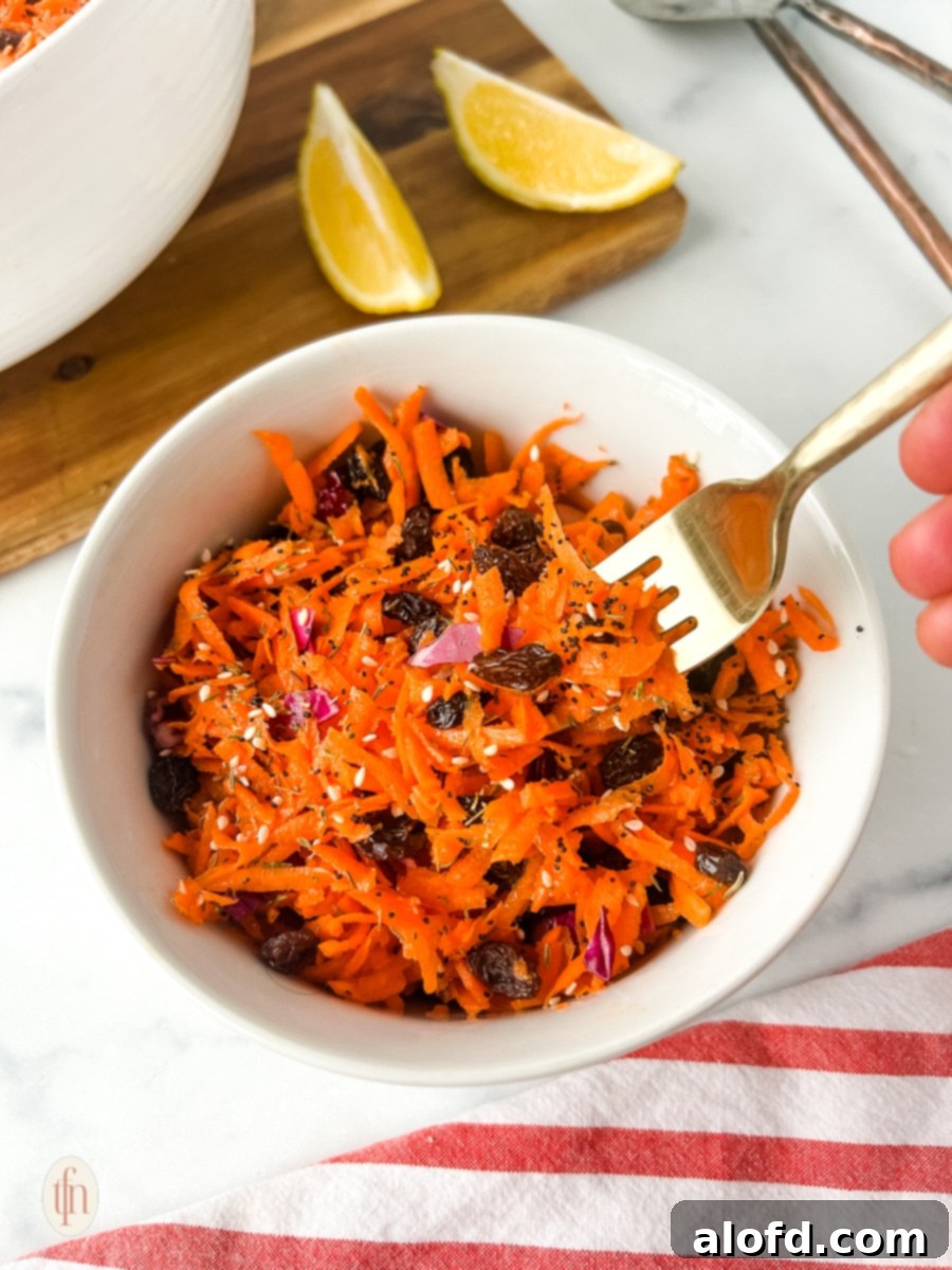 A serving of shredded carrot salad in a white bowl, ready to enjoy.