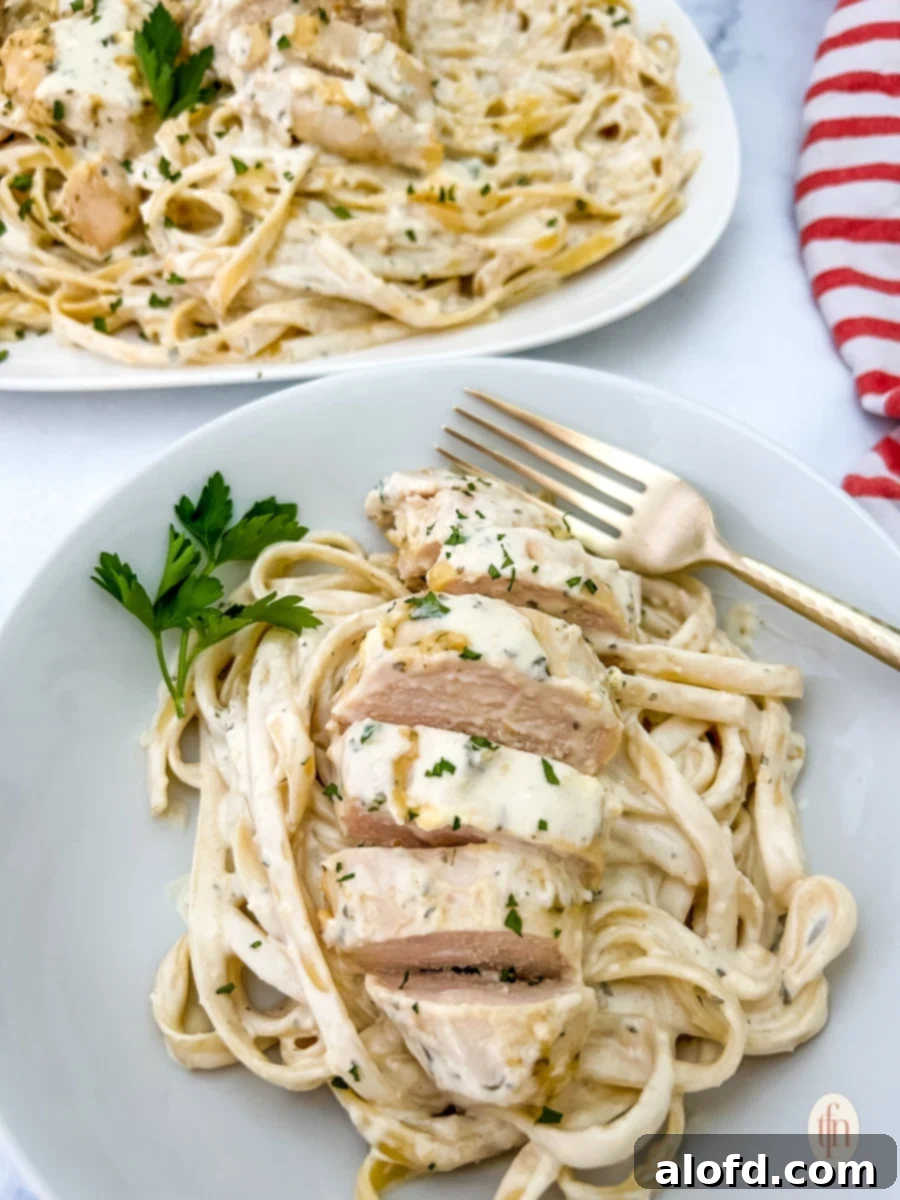 Creamy Garlic Parmesan Chicken Pasta 2 A hearty serving of creamy garlic parmesan chicken pasta in a white bowl, ready to be enjoyed with a fork.