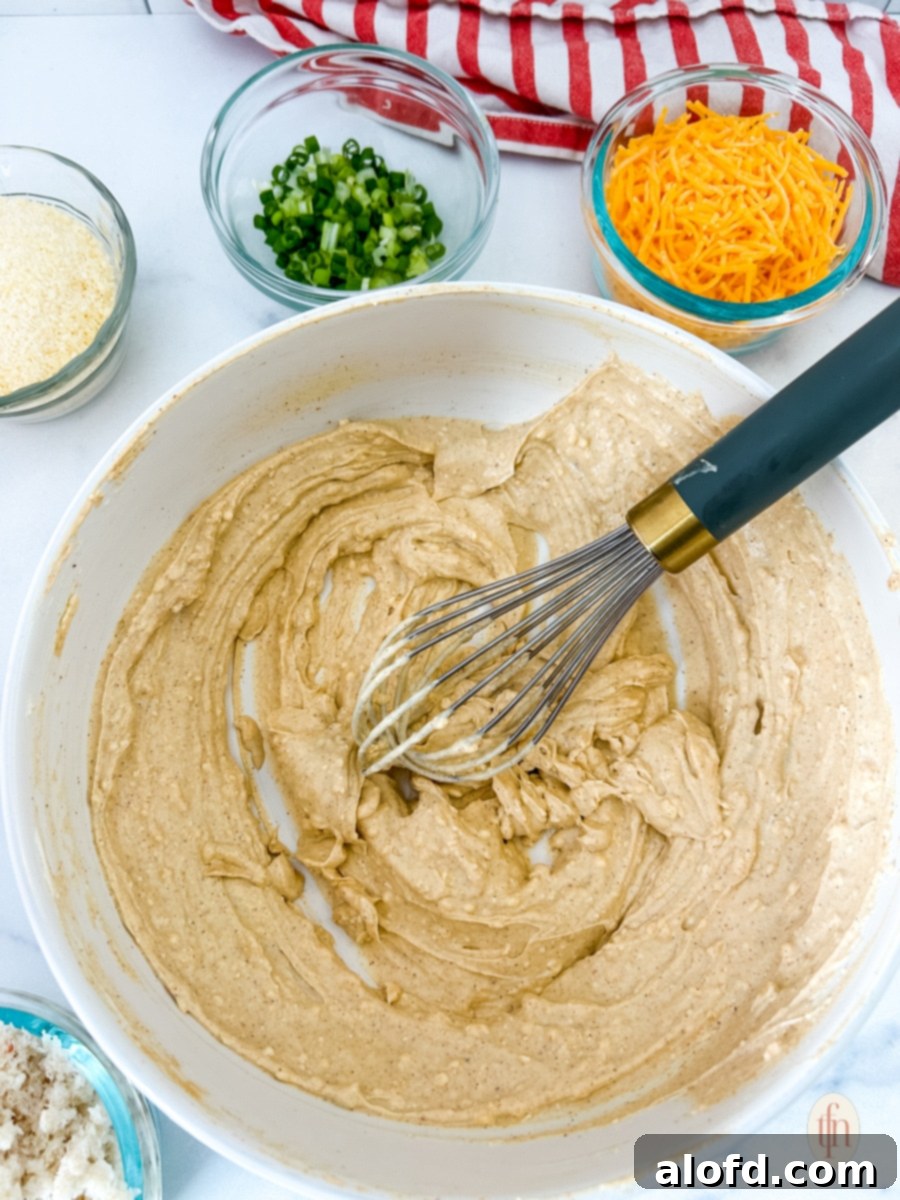 Mixing cream cheese and seasonings in a bowl with a whisk for the Cajun crab dip.