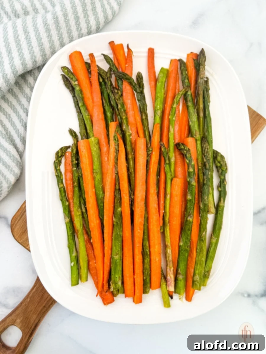 Golden Roasted Carrots and Asparagus 2 A beautifully arranged plate of roasted carrots and asparagus on a rustic wooden board, showcasing their vibrant colors and appealing texture.