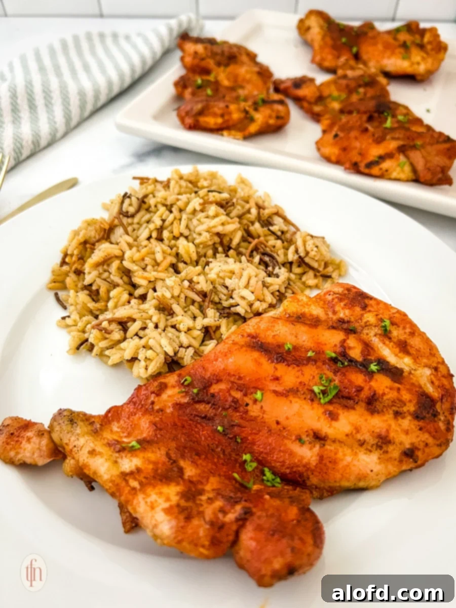 Smoked chicken thigh with rice on a white plate plus a platter.