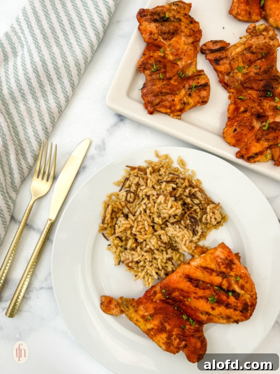 Smoked chicken thigh with rice on a white plate plus a platter.