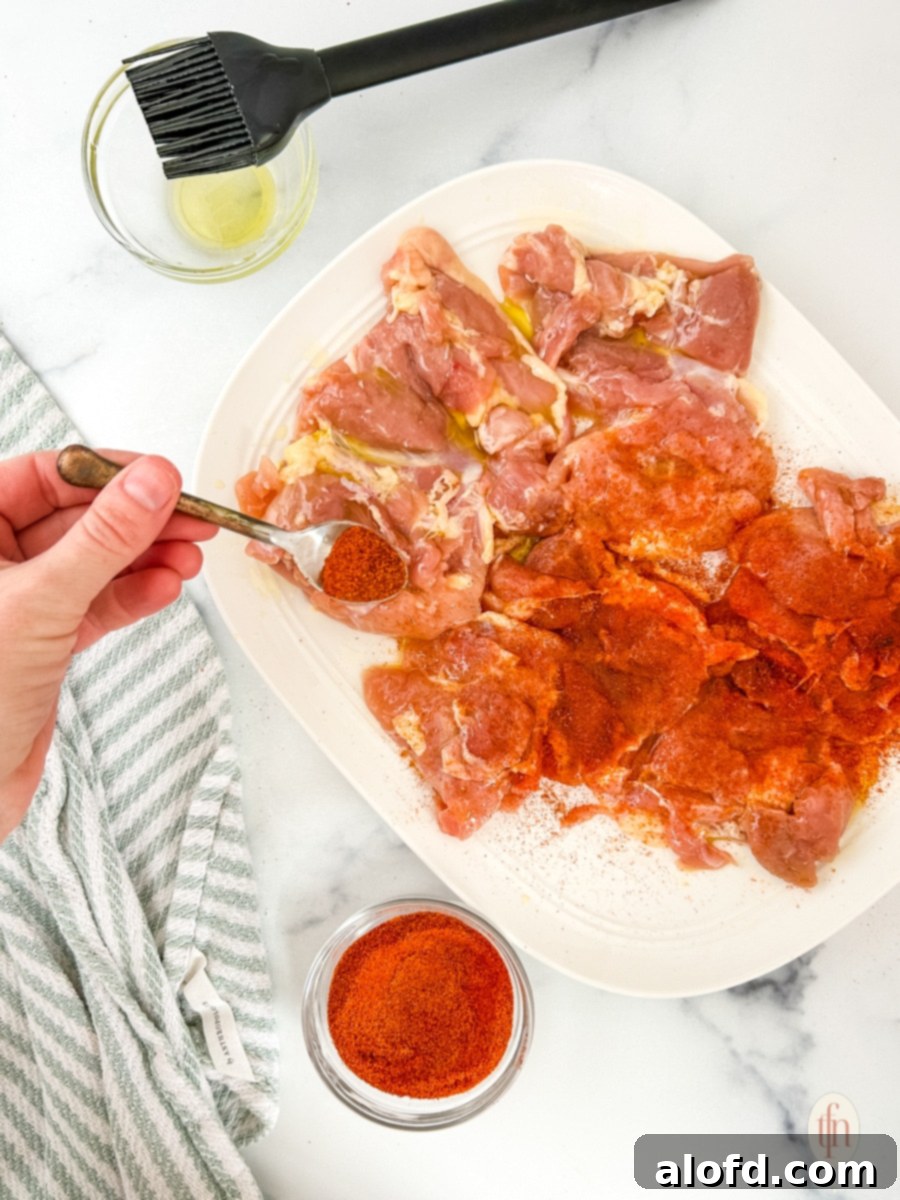 Adding seasoning to the chicken thighs.