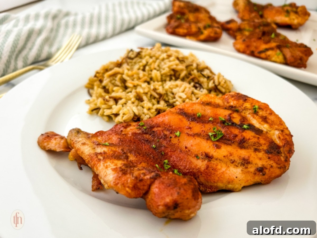 Smoked chicken thigh with rice on a white plate plus a platter.