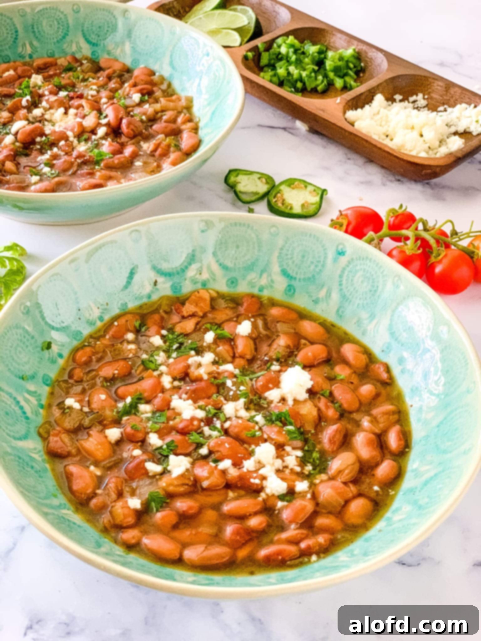 Speedy Instant Pot Pinto Beans 2 Close up of two bowls of ultimate instant pot pinto beans, garnished with fresh cilantro and a lime wedge.