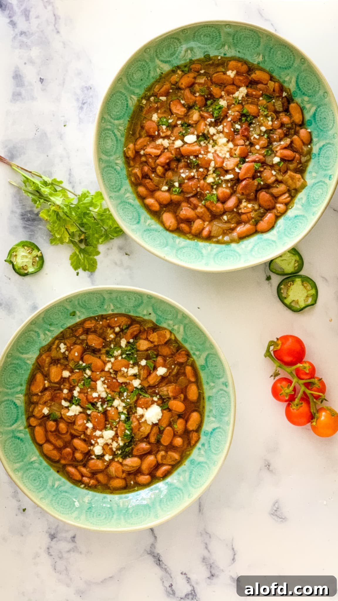 Speedy Instant Pot Pinto Beans 8 Two green bowls of pinto beans made from the ultimate pinto beans recipe, garnished.