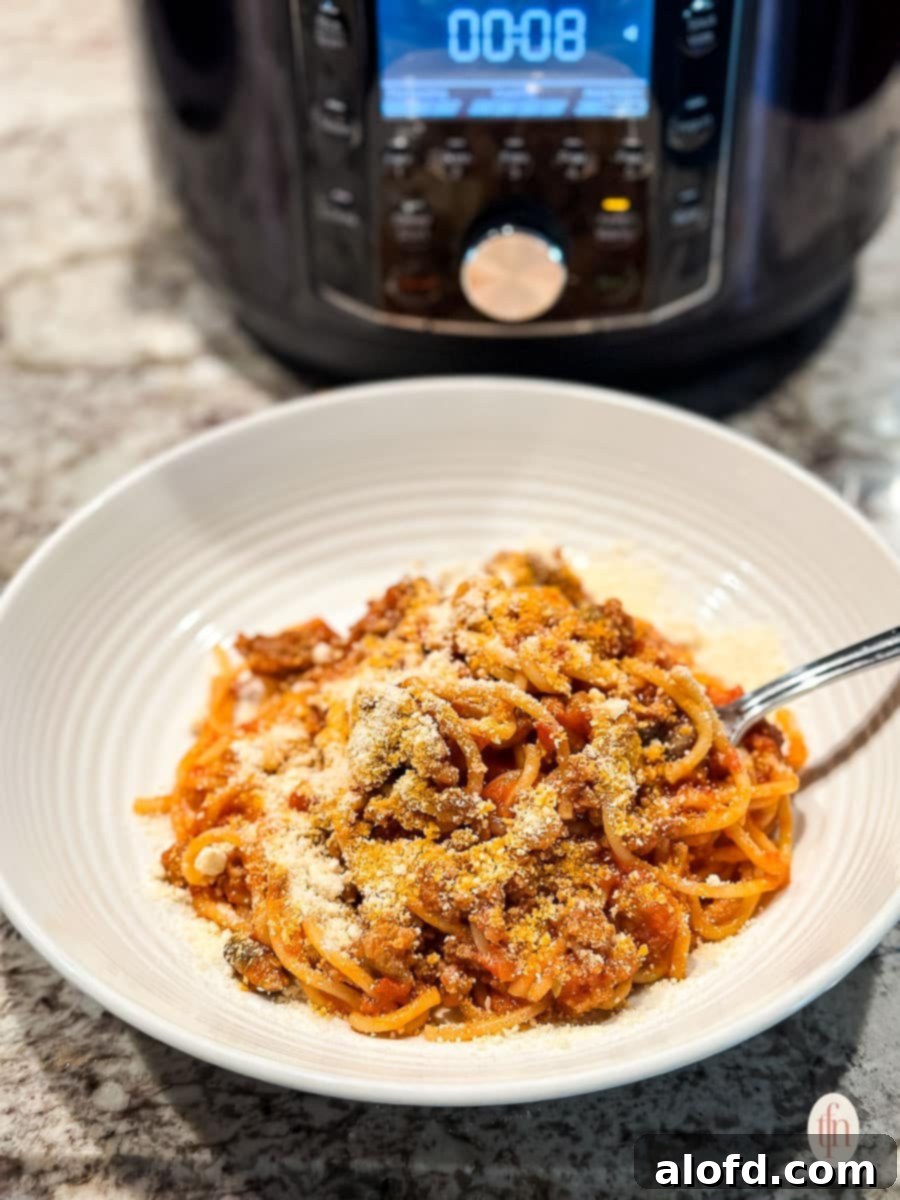 A bowl of spaghetti with an Instant Pot visible in the background.