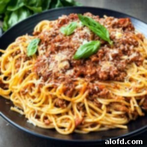 A plated bowl of spaghetti garnished with fresh basil and grated parmesan cheese.