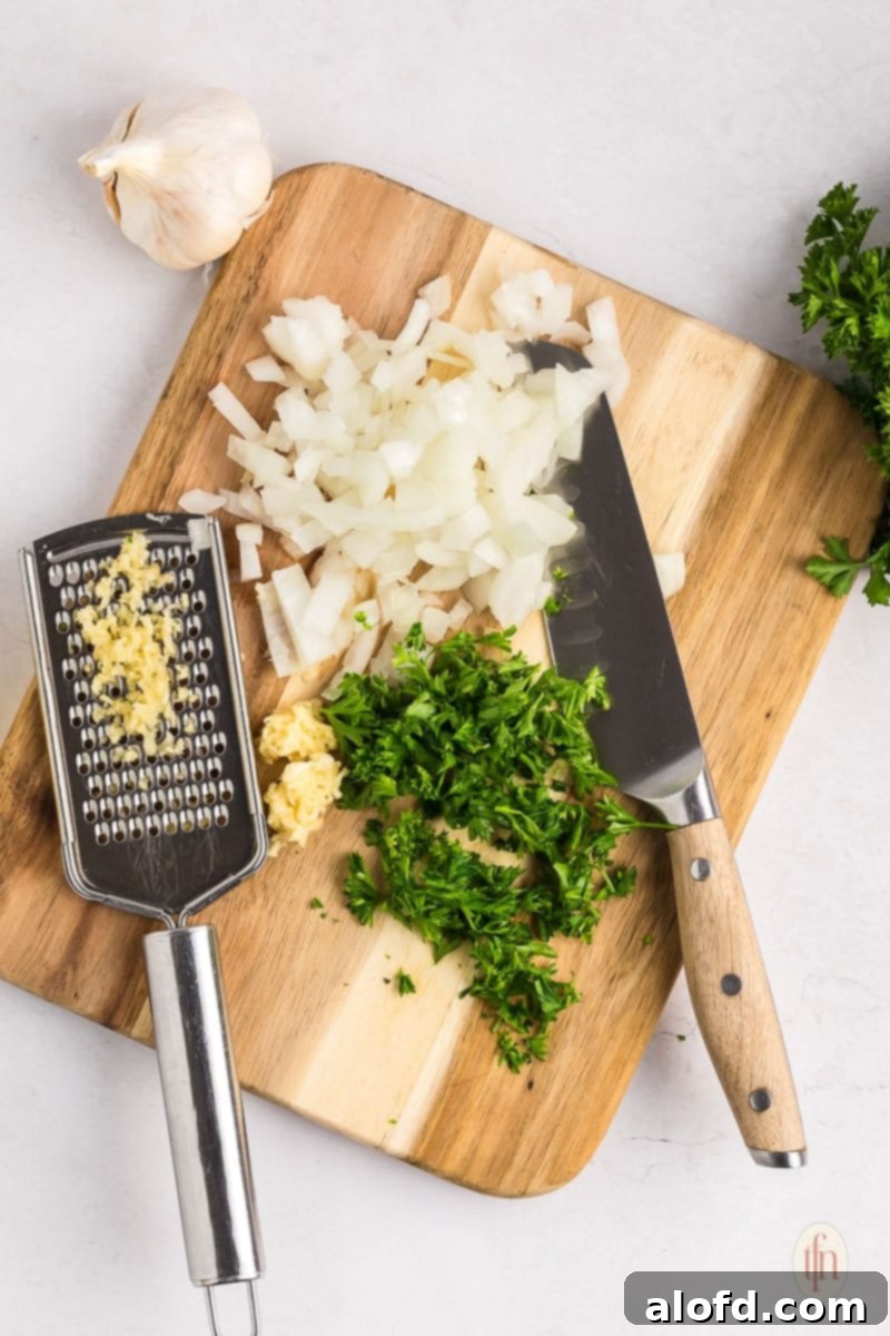 Sweet and Tangy Slow Cooker Honey Mustard Chicken 5 cutting board with knife, chopped parsley and onions, with grated garlic.