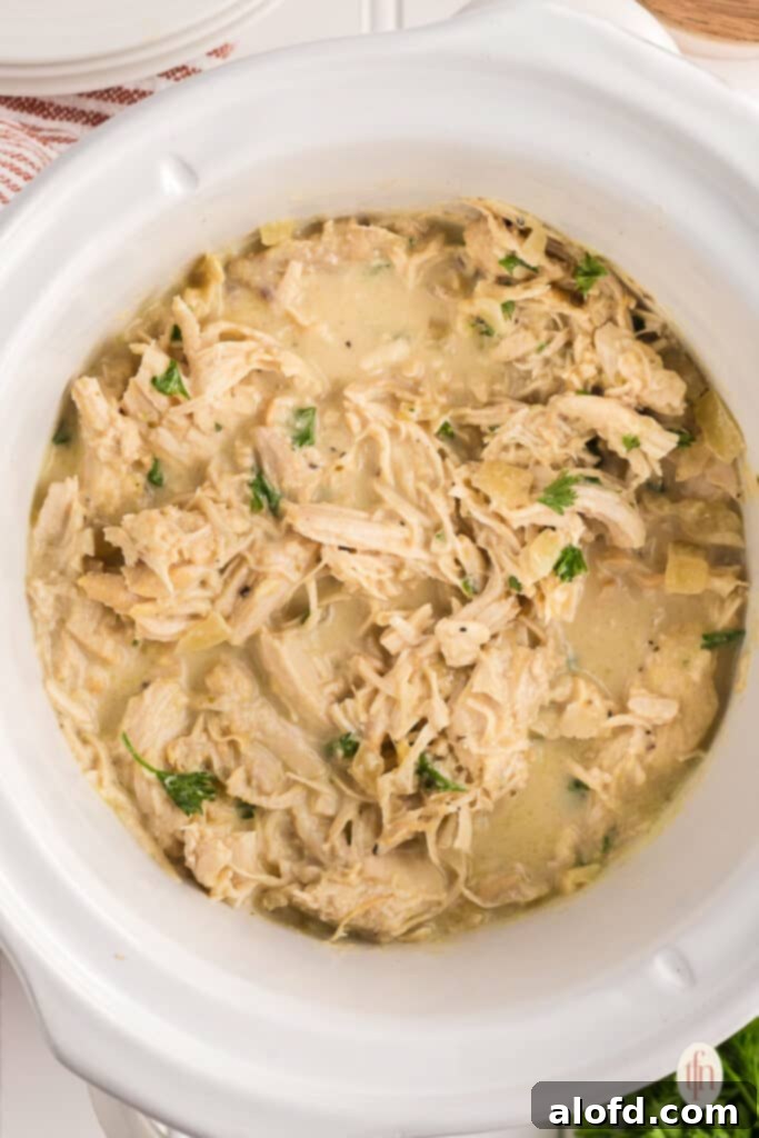 Sweet and Tangy Slow Cooker Honey Mustard Chicken 9 shredded chicken in the bowl of a slow cooker.