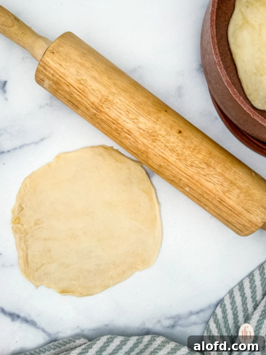 Artisan Sourdough Flatbread 7 Rolled sourdough flatbread dough with a rolling pin on a floured surface.