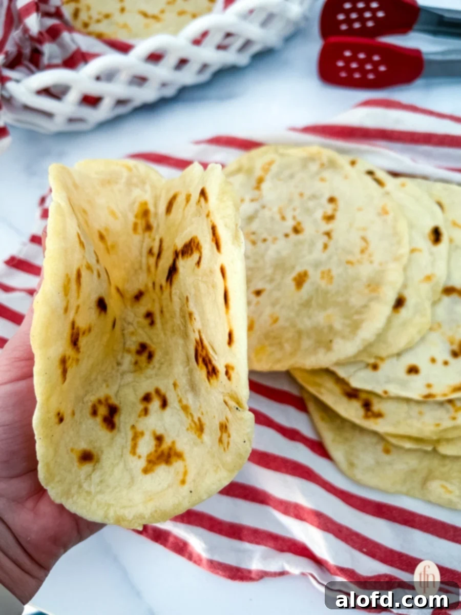 Artisan Sourdough Flatbread 10 A stack of golden-brown sourdough flatbreads on a red kitchen towel, perfectly cooked.
