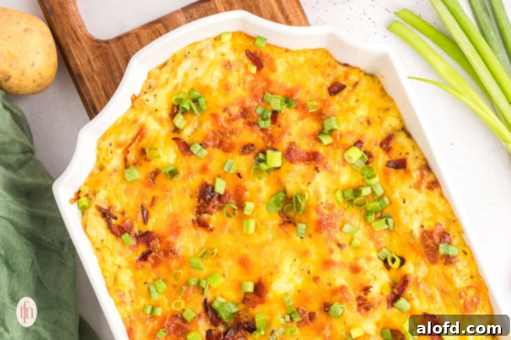 A casserole dish filled with golden-brown baked mashed potatoes, garnished with fresh green onions and crispy bacon.