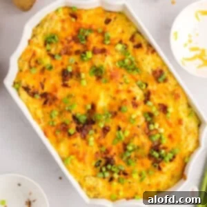 A casserole dish of golden-brown baked mashed potatoes, topped with crispy bacon and vibrant green onions.