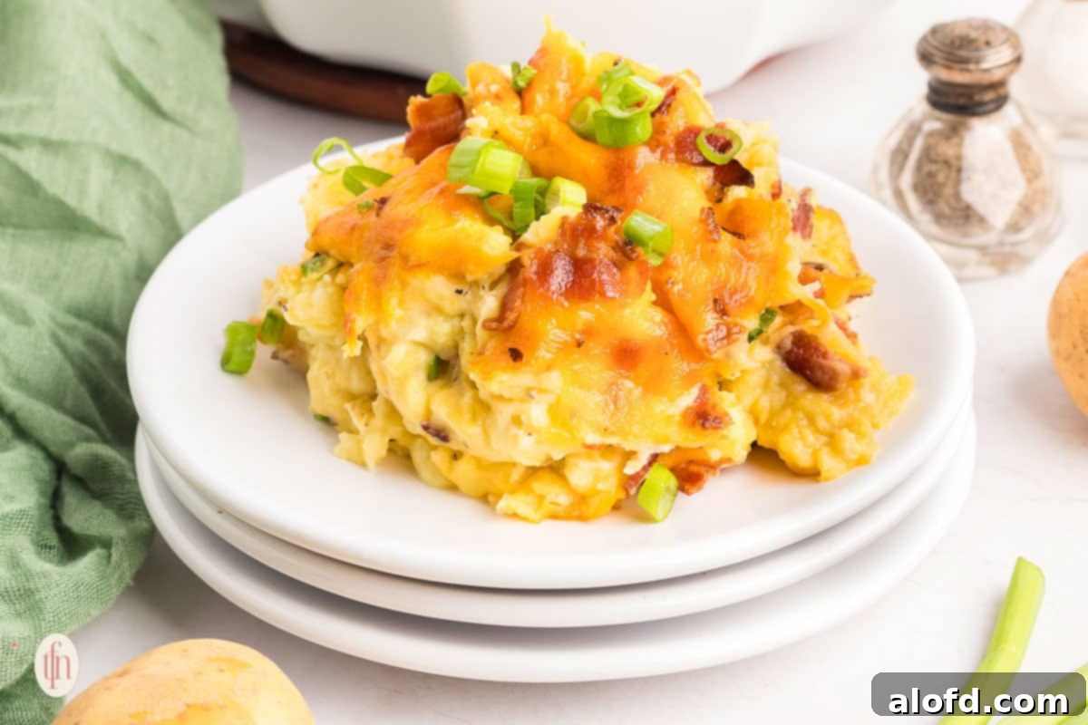 A white plate showcasing a serving of fluffy and cheesy twice baked mashed potatoes, topped with crispy bacon and fresh green onions.