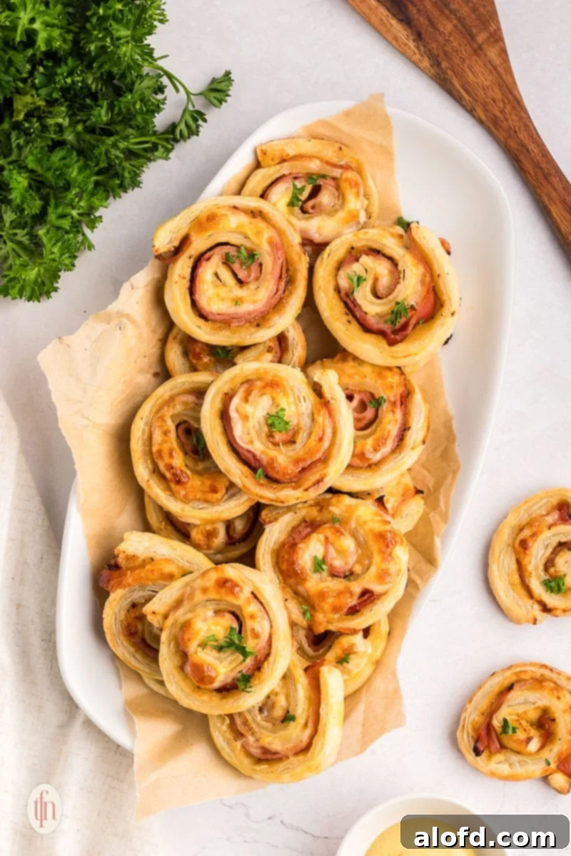 Ham and cheese roll-ups arranged neatly on a white serving platter, ready to be enjoyed.