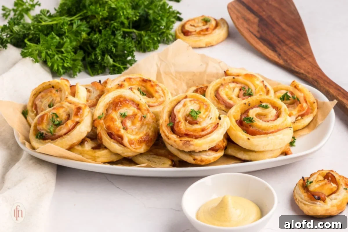 Freshly baked ham and cheese pinwheels beautifully arranged on a white serving platter, ready for guests.