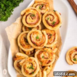 Ham and cheese pinwheels on a serving platter, showcasing their golden-brown perfection.