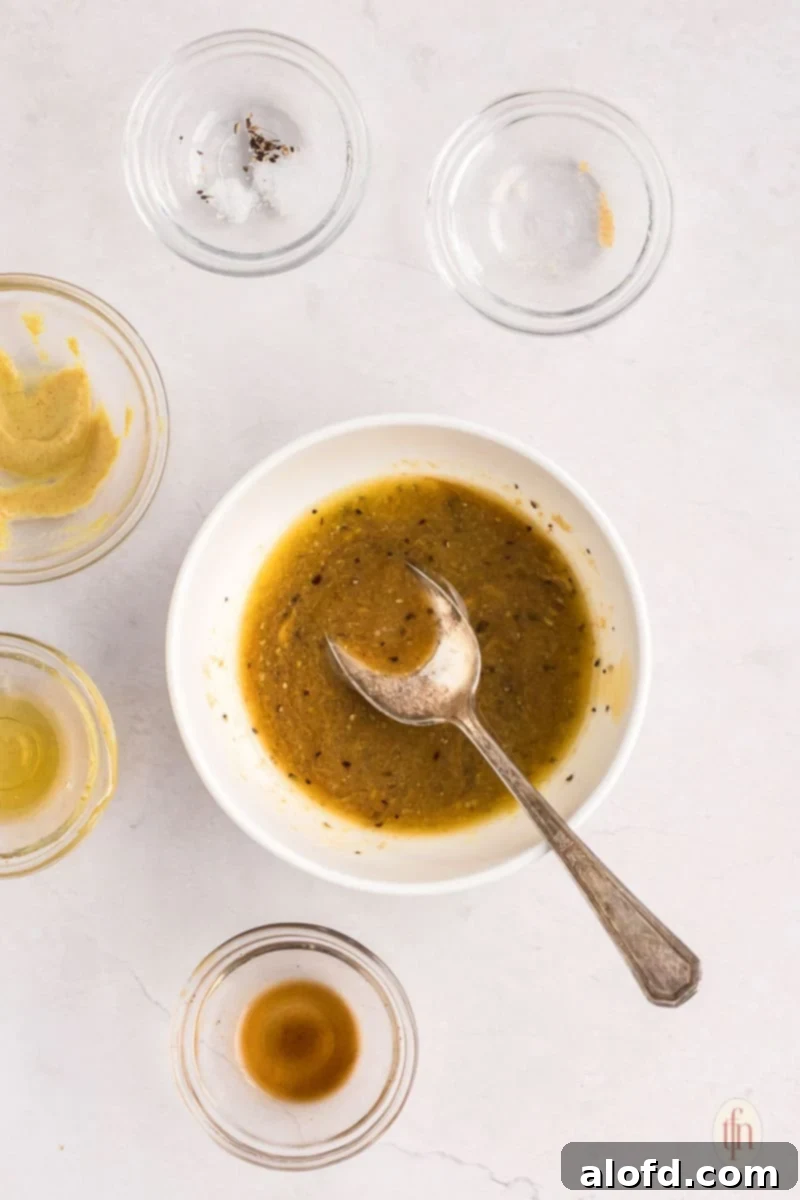 A white bowl filled with the mixed butter and mustard sauce, ready to be spread onto the puff pastry for ham and cheese pinwheels.