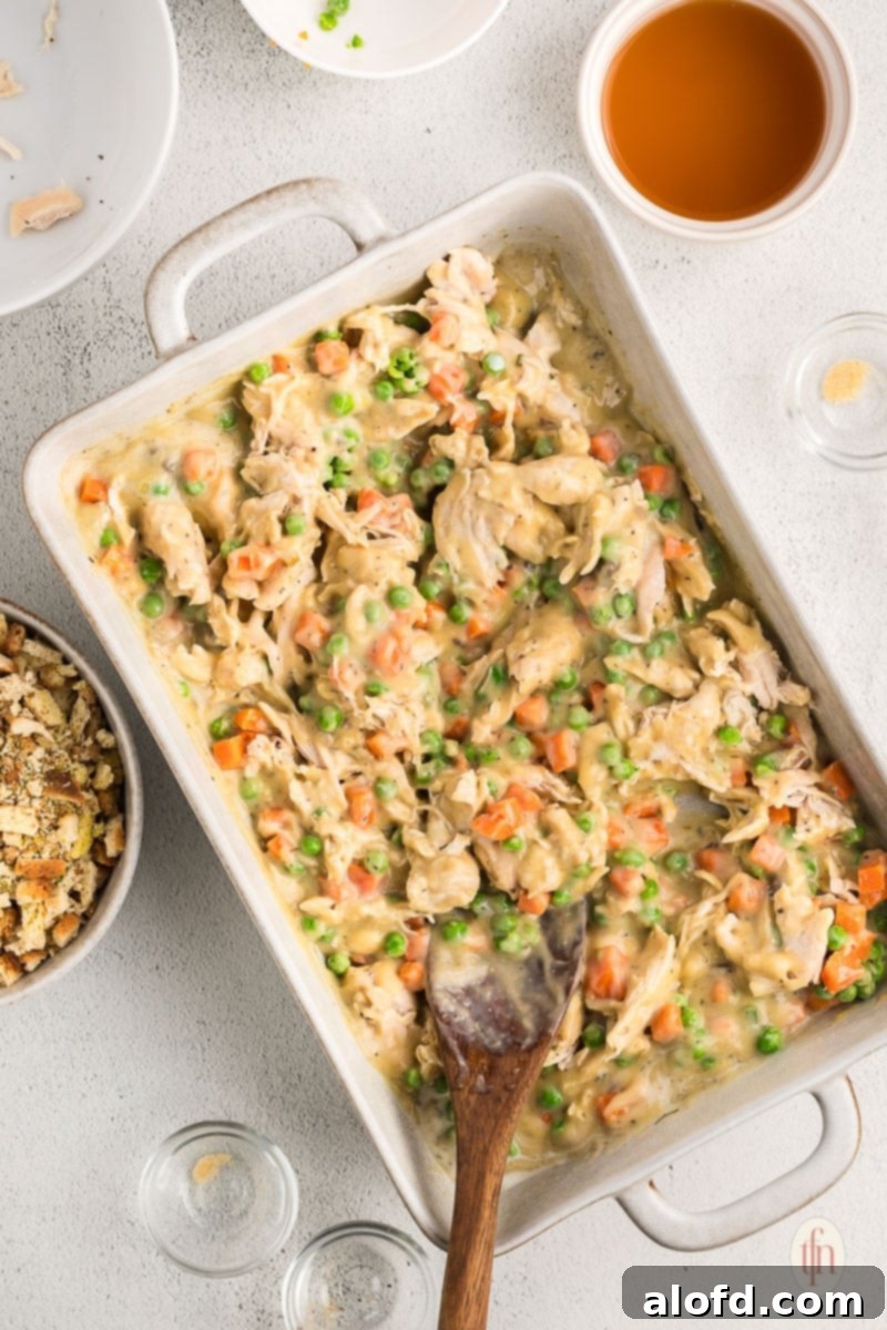 The chicken, vegetables, and creamy sauce are mixed and ready to be topped with the Stove Top stuffing before baking, showcasing the layers.