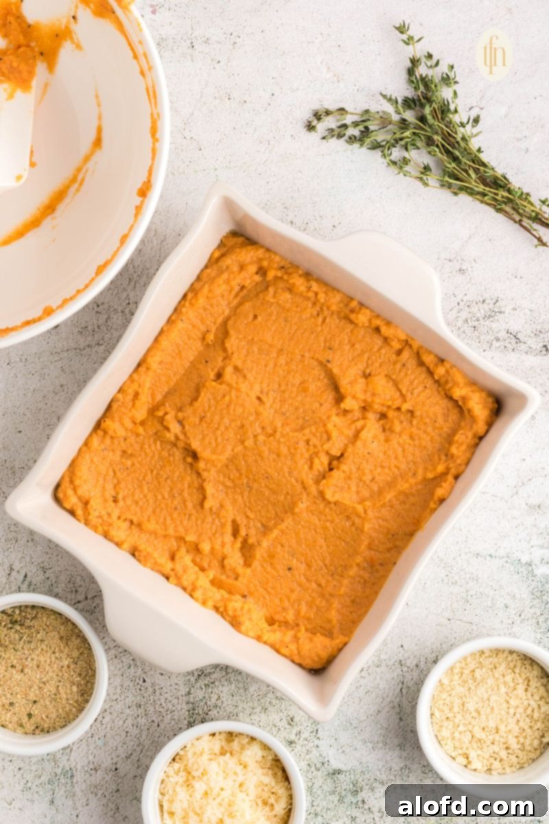 Smooth sweet potato mixture in a white casserole dish, ready for topping.