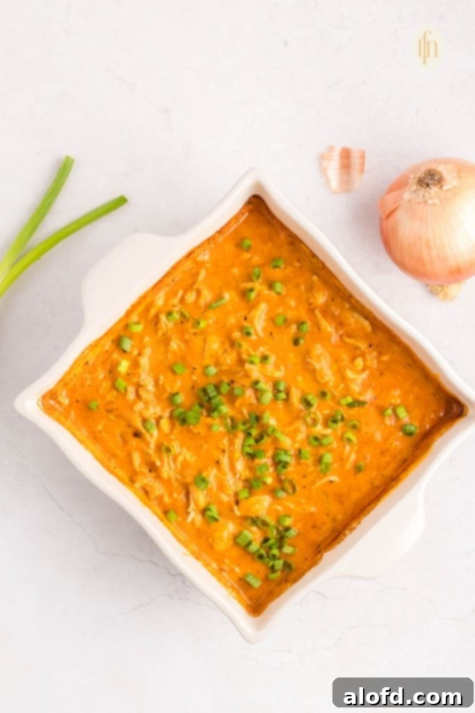 Creamy Dairy-Free Buffalo Chicken Dip 12 The finished dairy-free buffalo chicken dip, garnished generously with fresh green onions, presented in a white baking dish, ready to be served as a tantalizing appetizer.
