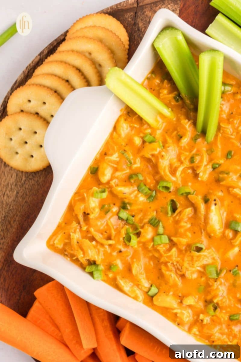 Creamy Dairy-Free Buffalo Chicken Dip 13 A beautifully arranged platter featuring warm dairy-free buffalo chicken dip, surrounded by a colorful assortment of dippers including tortilla chips, fresh celery, and crisp carrots, perfect for a party.