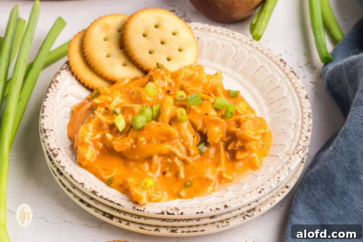 Creamy Dairy-Free Buffalo Chicken Dip 14 An inviting horizontal shot of warm dairy-free buffalo chicken dip in a rustic bowl, surrounded by a variety of dippers on a wooden board, ready for sharing at a gathering.