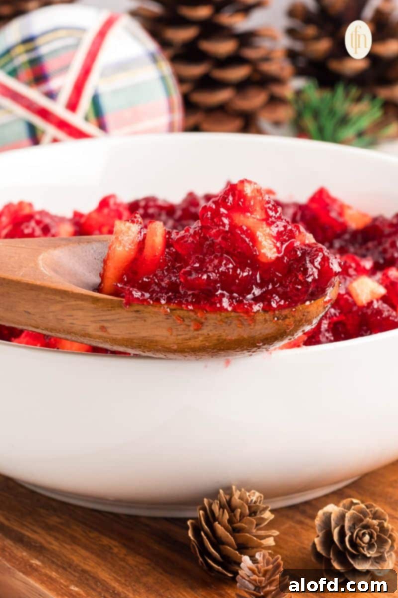 A wooden spoon scooping a portion of the set fruit jello mixture from a white bowl, showcasing its firm yet tender texture.