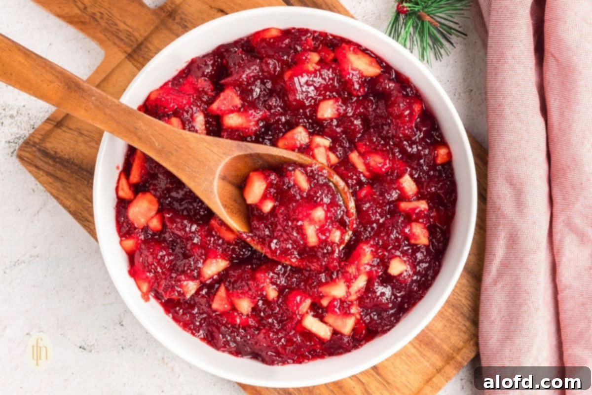 A wide shot of the jello mixture in a white bowl with a wooden spoon, showcasing the festive red color.