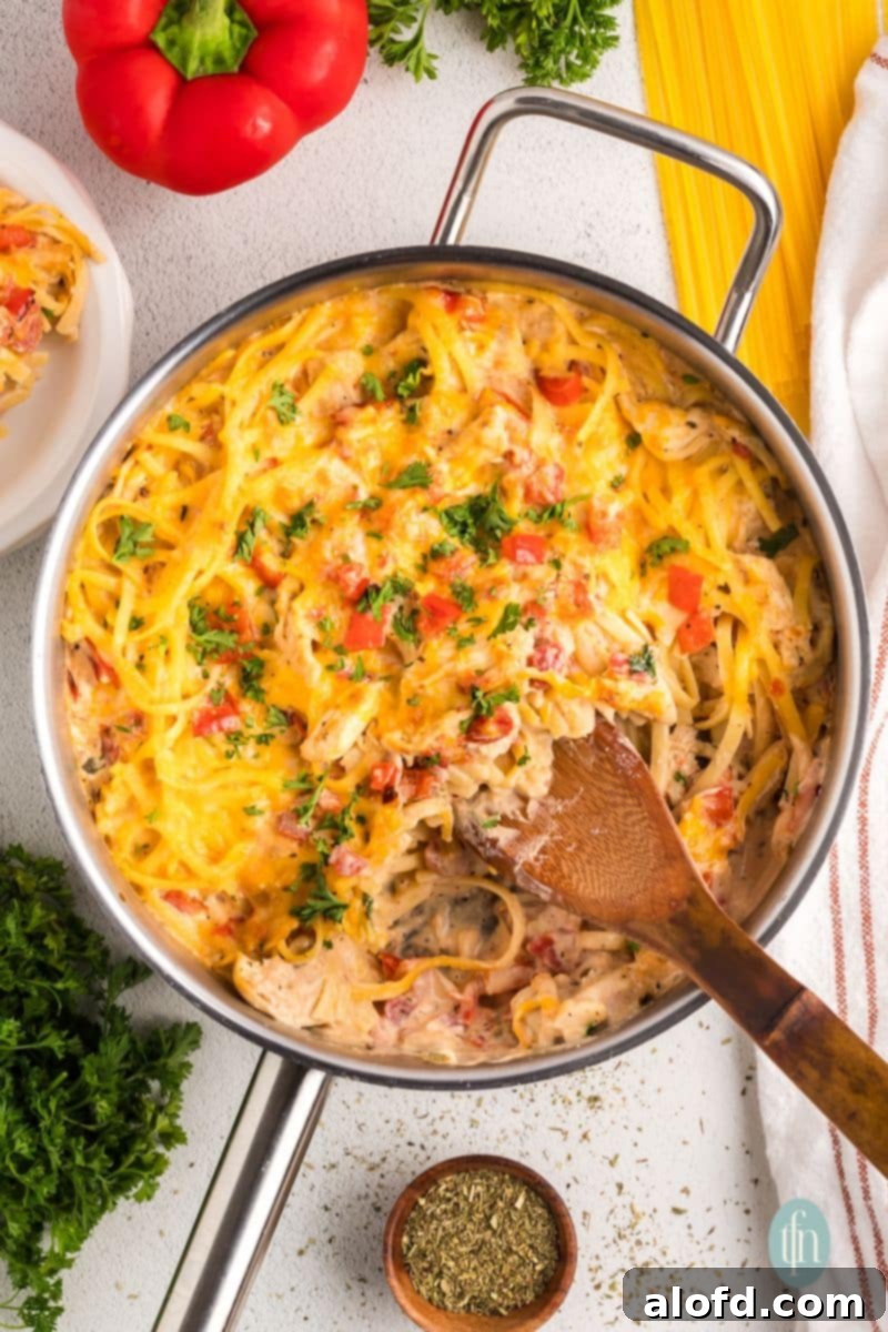 Spicy Rotel Chicken Spaghetti Casserole 16 A large serving of creamy Rotel chicken spaghetti in a pan with a wooden spoon, perfect for sharing.