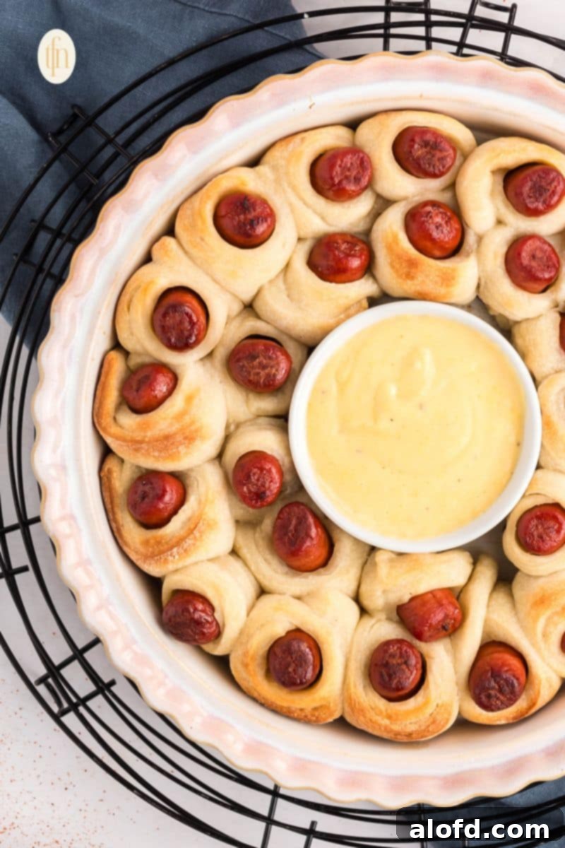 Loaded Pigs in a Blanket Bake 2 A baking dish of pigs in a blanket with a cup of sauce in the middle.