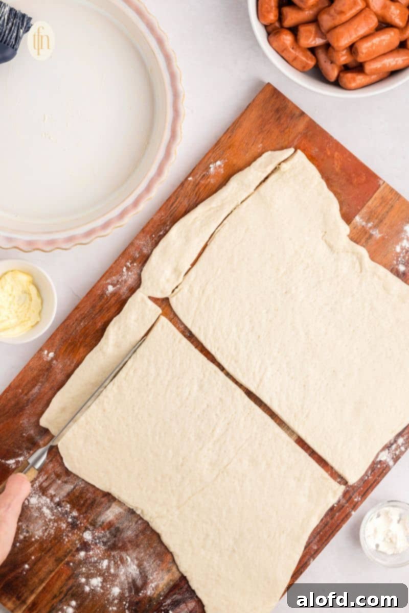 Loaded Pigs in a Blanket Bake 9 Slicing the flatten dough on a wooden board.