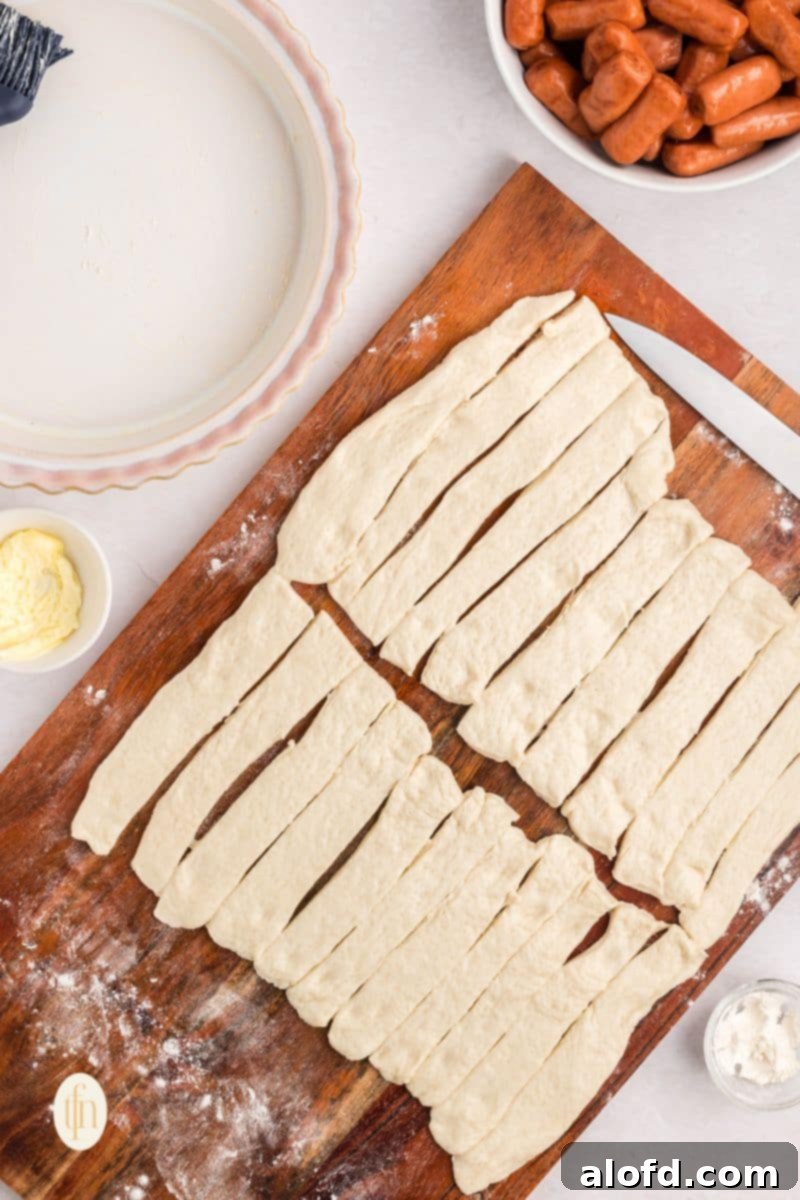 Loaded Pigs in a Blanket Bake 10 Sliced dough on a wooden board.