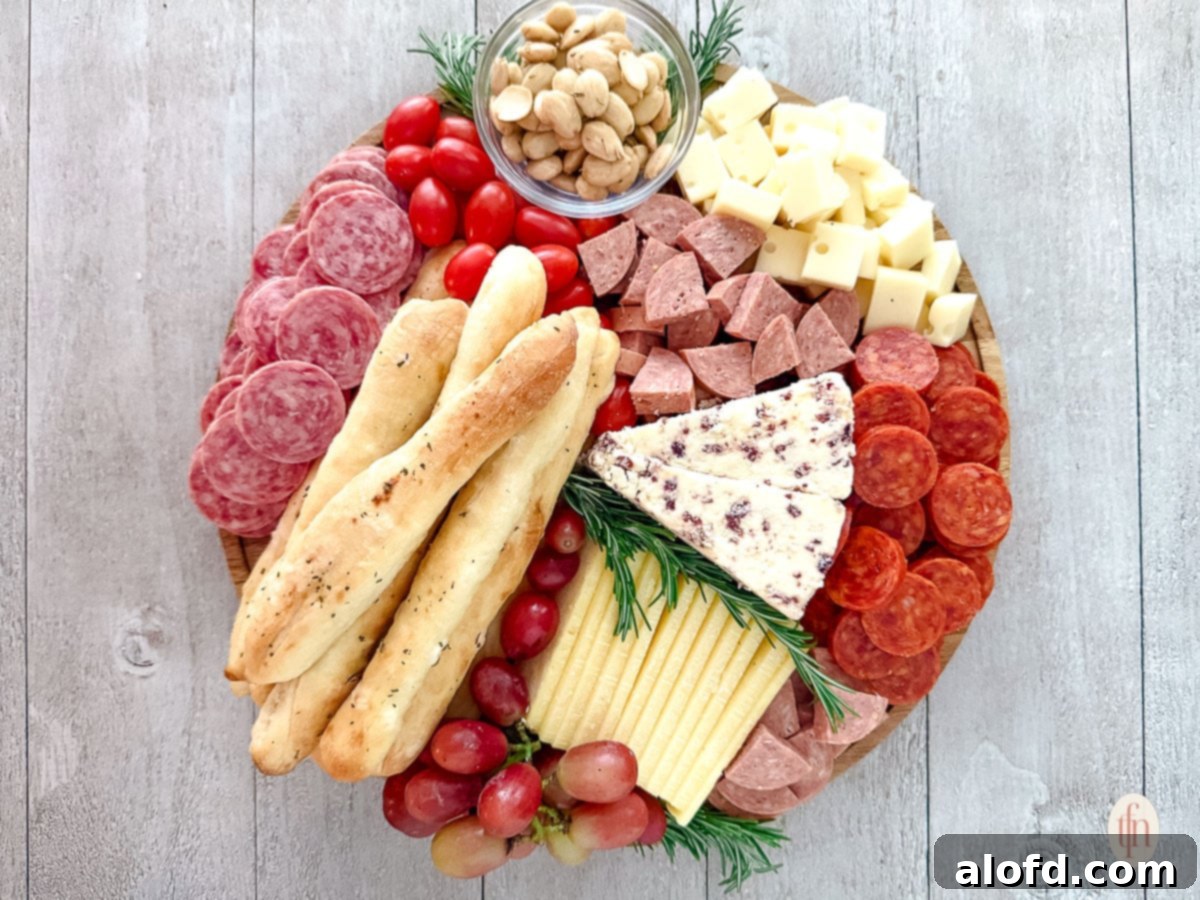 Effortless Charcuterie Boards 12 A beautifully presented round charcuterie board, filled with an abundance of cured meats, various cheeses, homemade breadsticks, cherry tomatoes, grapes, and almonds, ready for guests.