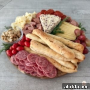 Effortless Charcuterie Boards 13 A round charcuterie board mixed with bread, meat, tomatoes, fruits, and cheese.