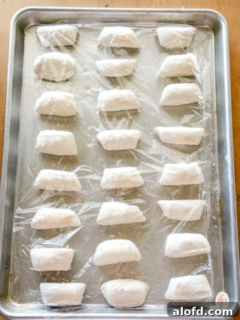 Effortless Charcuterie Boards 5 Small batch of Bridgford Parkerhouse-Style Rolls dough thawing on a baking sheet, covered with plastic wrap.