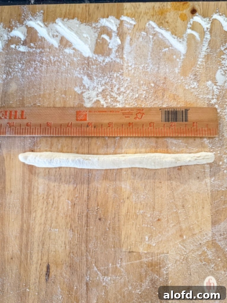 Effortless Charcuterie Boards 6 Dough log being measured with a ruler on a wooden board before cutting for breadsticks.