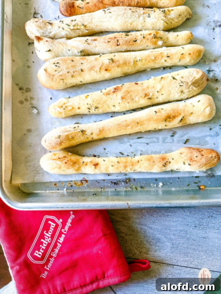 Effortless Charcuterie Boards 8 Freshly baked garlic herb breadsticks cooling on a baking sheet lined with parchment paper.