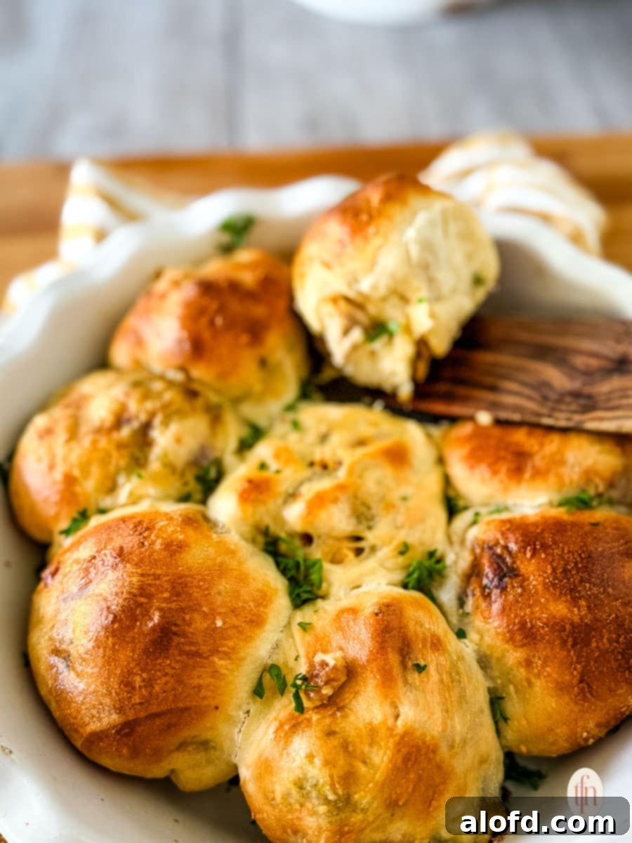 Reinventing Your Thanksgiving Turkey 8 Hands separating and serving warm, stuffed pull-apart dinner rolls from a baking dish.