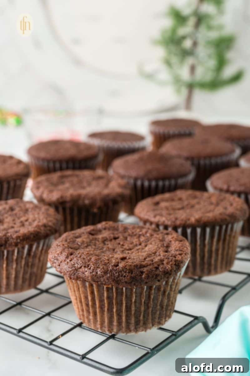 Decadent Peppermint Chocolate Cupcakes 13 Chocolate Peppermint Cupcakes with frosting and crushed candy canes on a cooling rack.