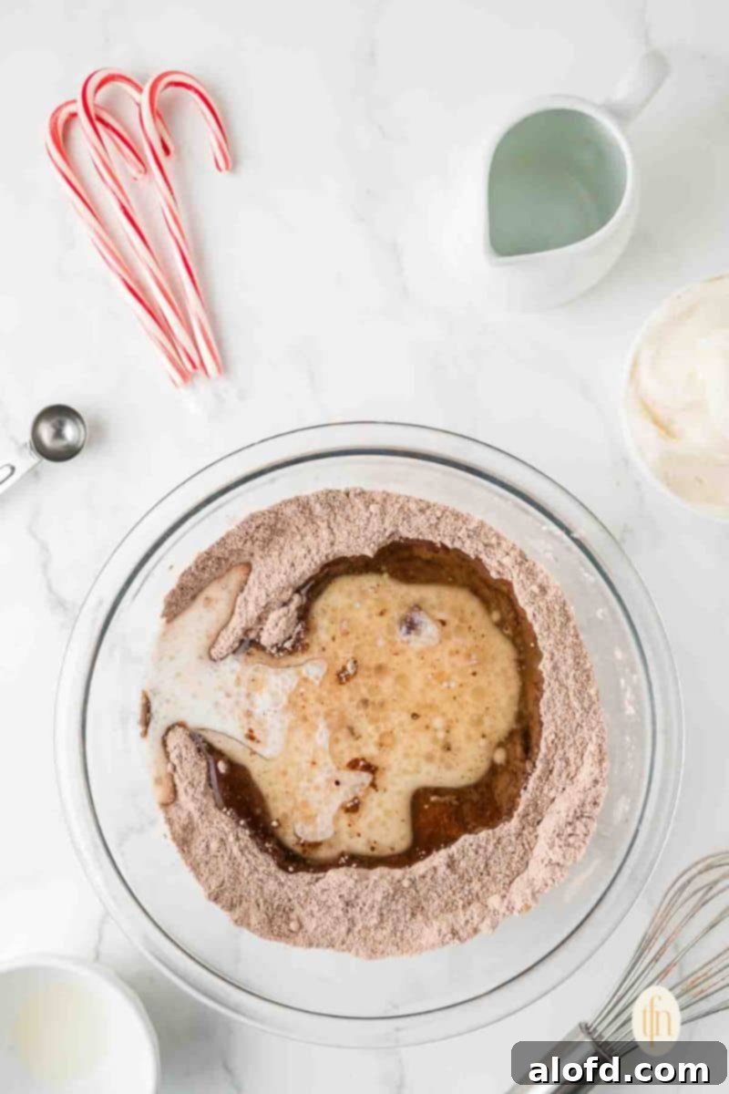 Decadent Peppermint Chocolate Cupcakes 7 Dry mixture in a glass bowl with the wet mixture poured into the middle, ready to be combined.