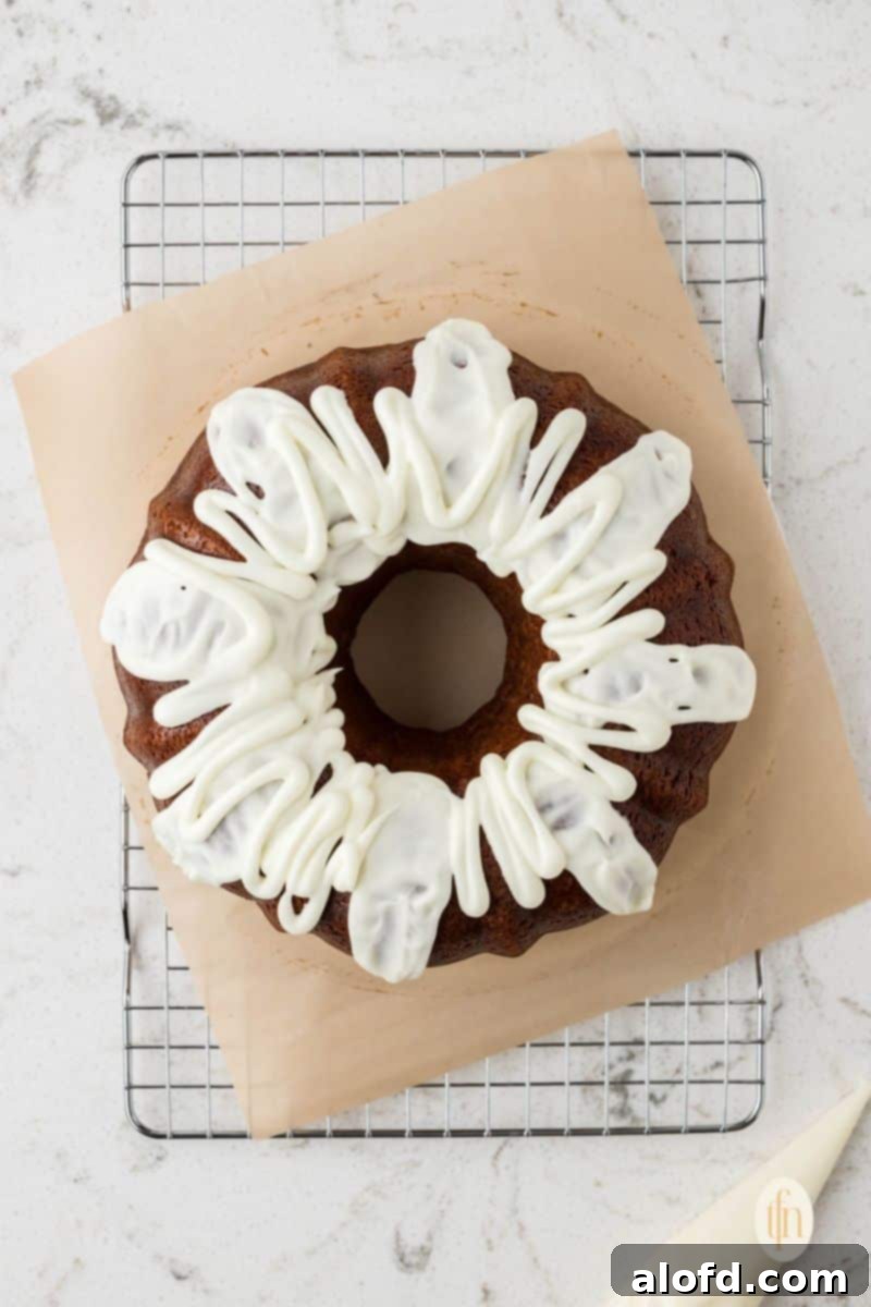 Spiced Molasses Bundt Cake 11 A beautifully baked gingerbread bundt cake, artfully drizzled with a rich vanilla glaze, resting on a wire rack to set before serving.